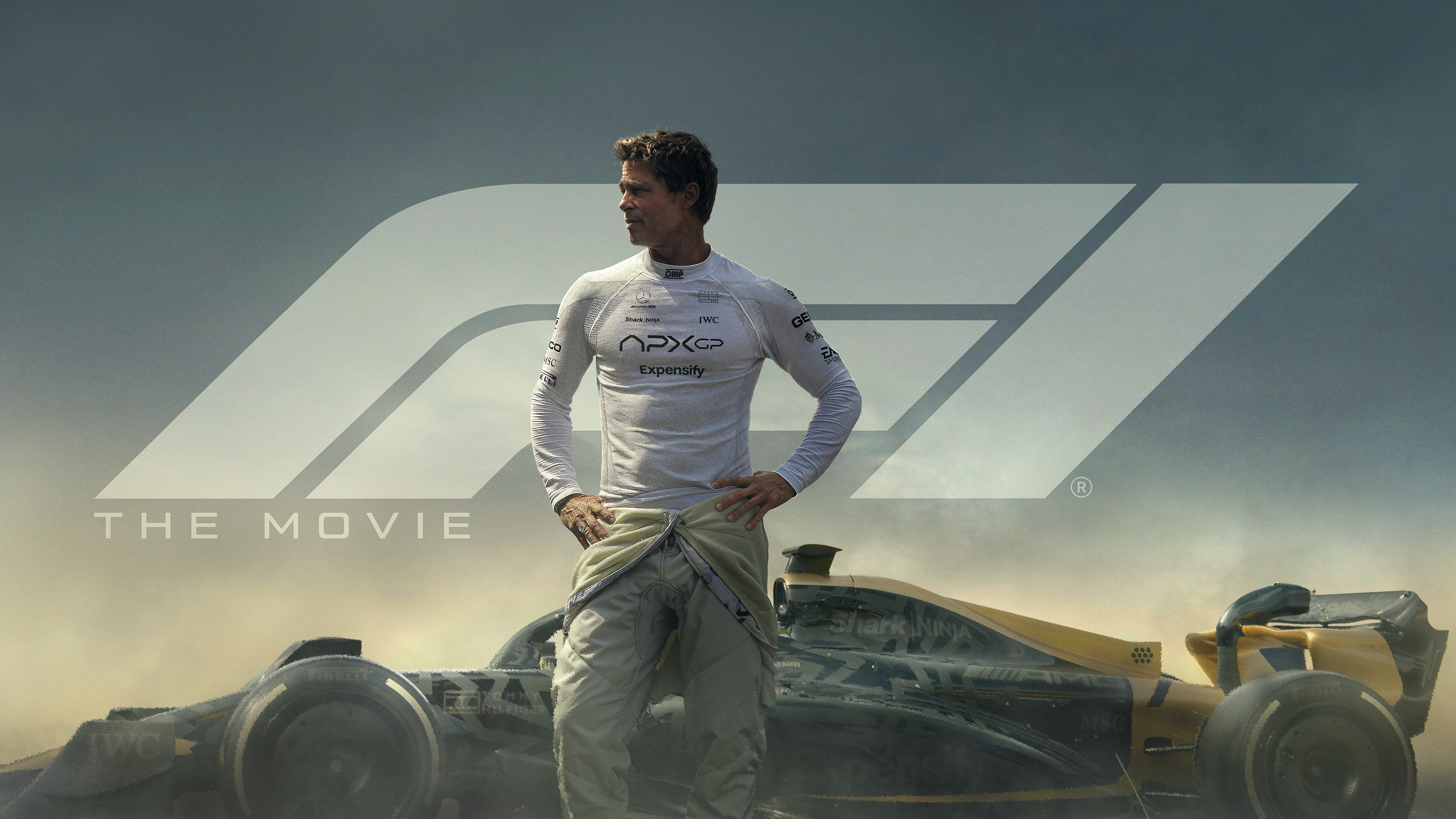 A poster from F1: The Movie featuring Brad Pitt standing in front of a Formula 1 car