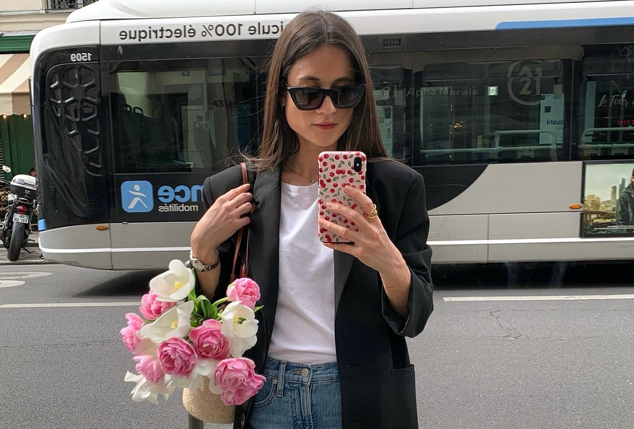 A French woman wearing a black blazer over a white tee and jeans.