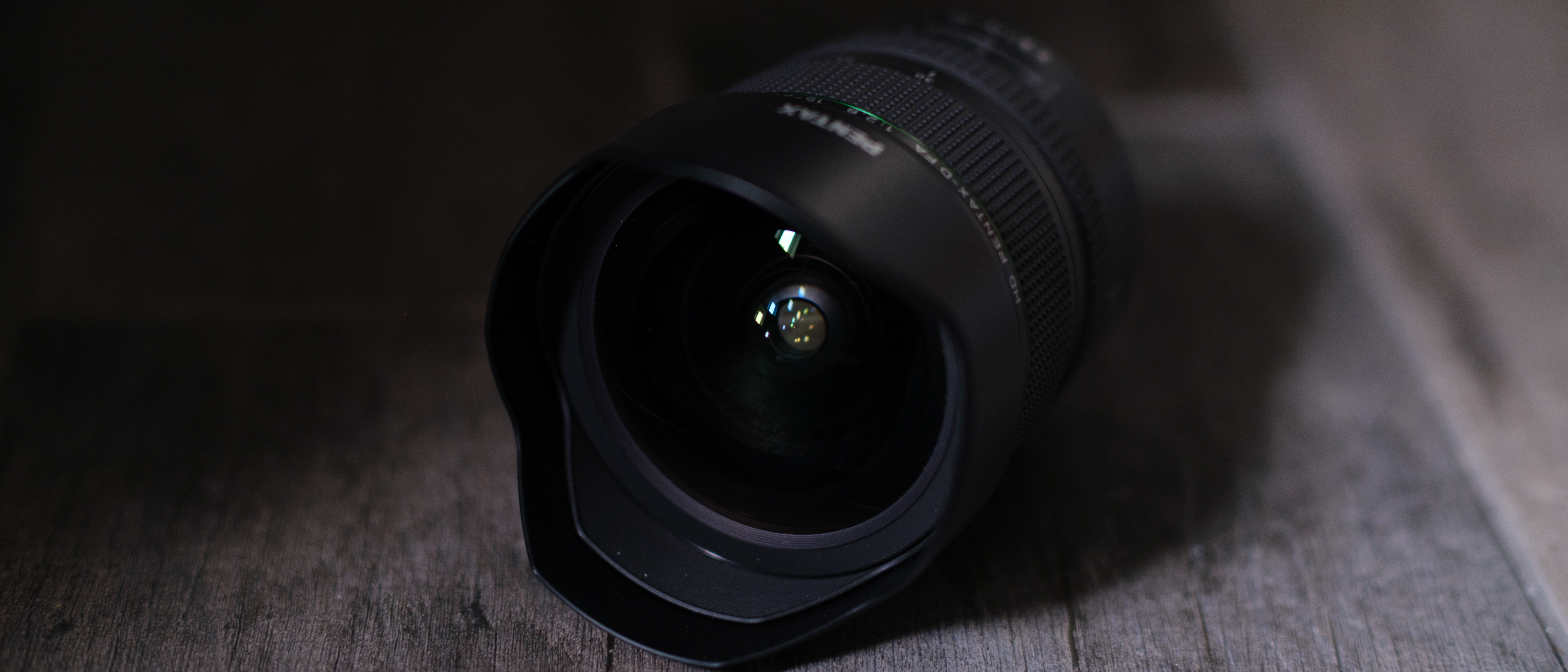 The Pentax 15-30mm f/2.8 on a gray wood background