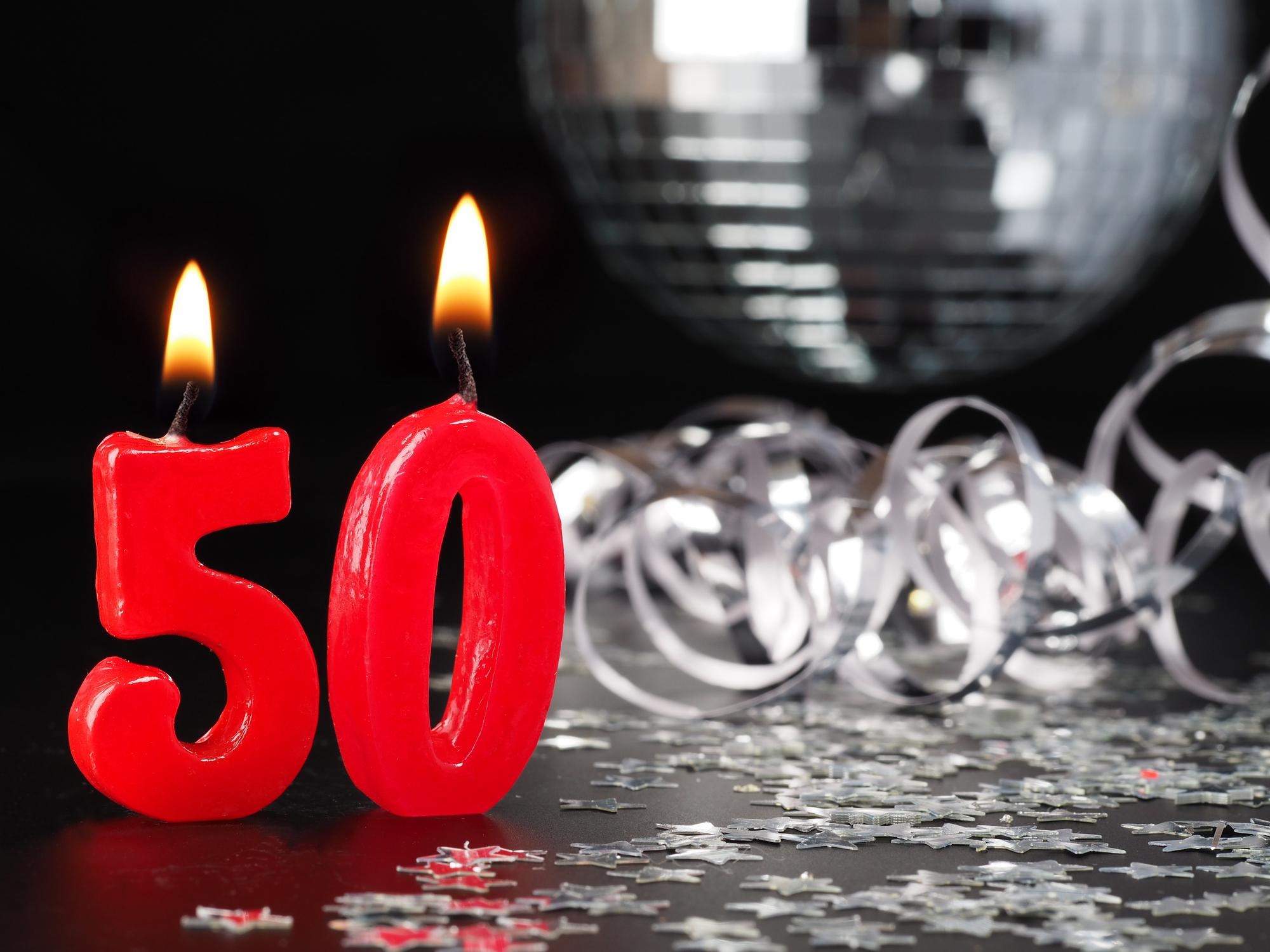 two red candles, one for the number 5 and one for the number 0, with a disco ball and silver confetti