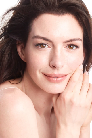 anne hathaway looking at the camera with glowing skin