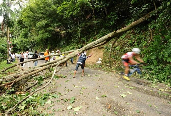 Race officials warn riders of a fallen tree on the 44 Kelok climb