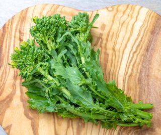 Fresh uncooked broccoli rabe on a wooden board