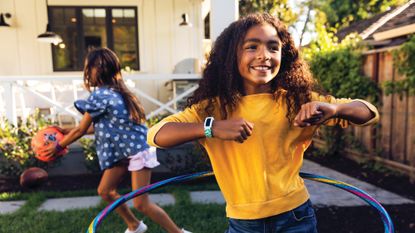 Children playing in a garden, both wearing the best smartwatch for kids – the Fitbit Ace 3