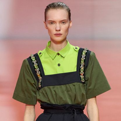 a model on the prada runway wearing an apron neckline jeweled collar
