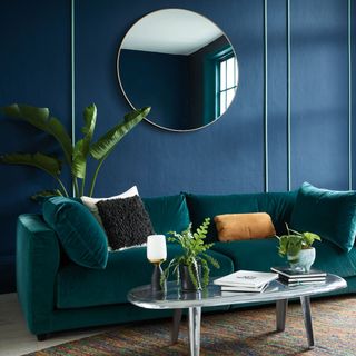 living room with blue wall and green velvet sofa