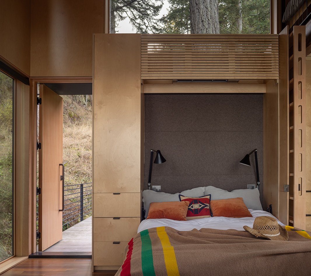 Blakely Island Cabin, a boxy structure raised on stilts above tree canopy in washington state forest