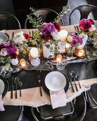 Dining table with candles, jewel colored flowers and monochrome plates