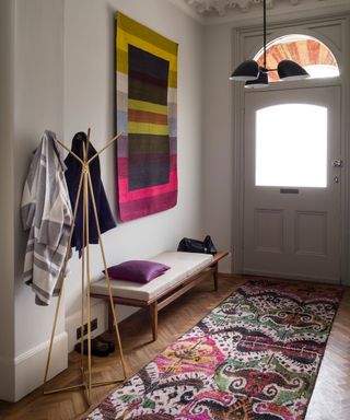 A purple and pink patterned runner and wall art in a neutral small hallway idea.
