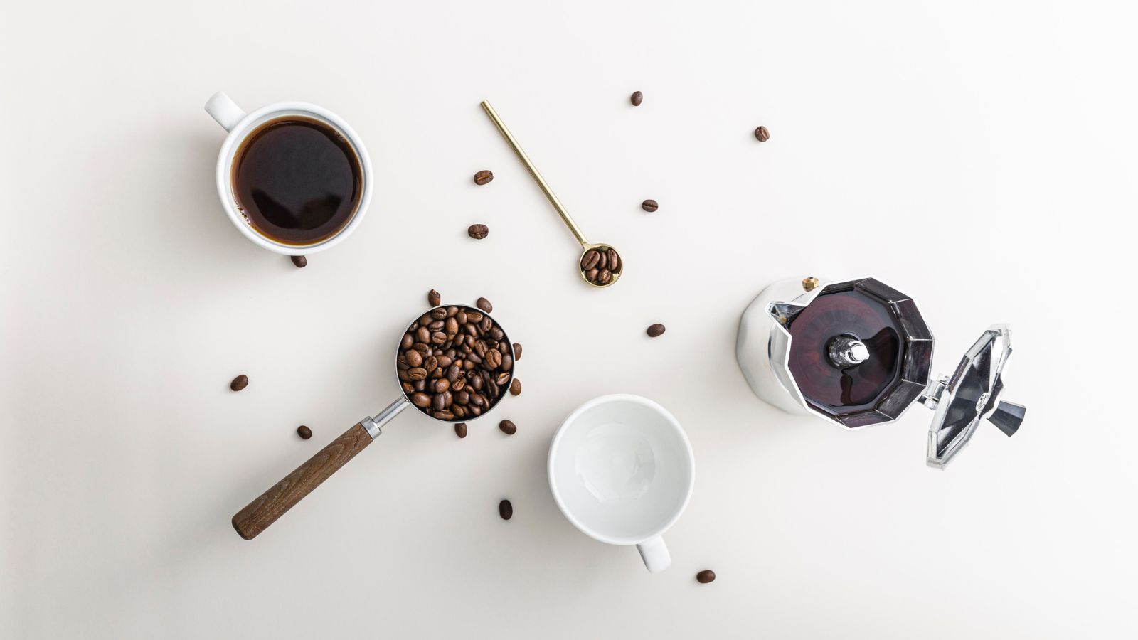 coffee beans, a coffee mug, a portafilter on a white background from a birdseye perspective