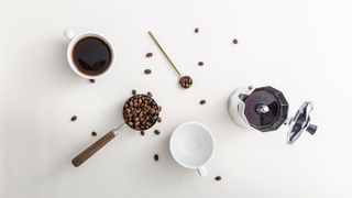 coffee beans, a coffee mug, a portafilter on a white background from a birdseye perspective