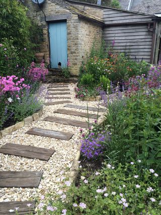 gravel path with railway sleepers curving through pretty flowerbeds