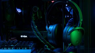 Audeze Maxwell wireless gaming headset for Xbox & PC with green lighting in front of open gaming desktop.