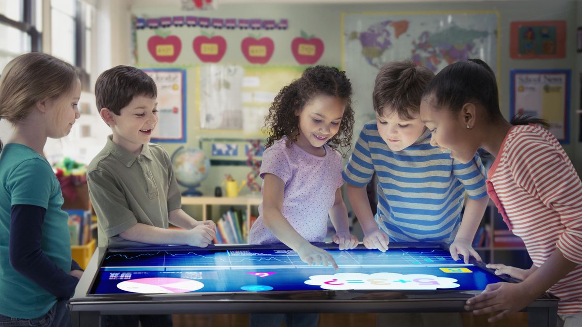 Smiling kids playing with technology in a classroom.