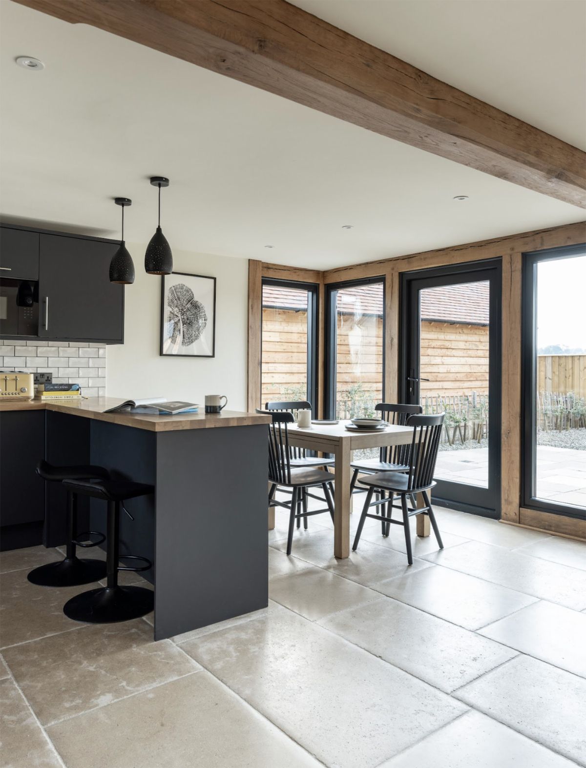 An open-plan kitchen-diner with floor to ceiling windows looking out to an external space