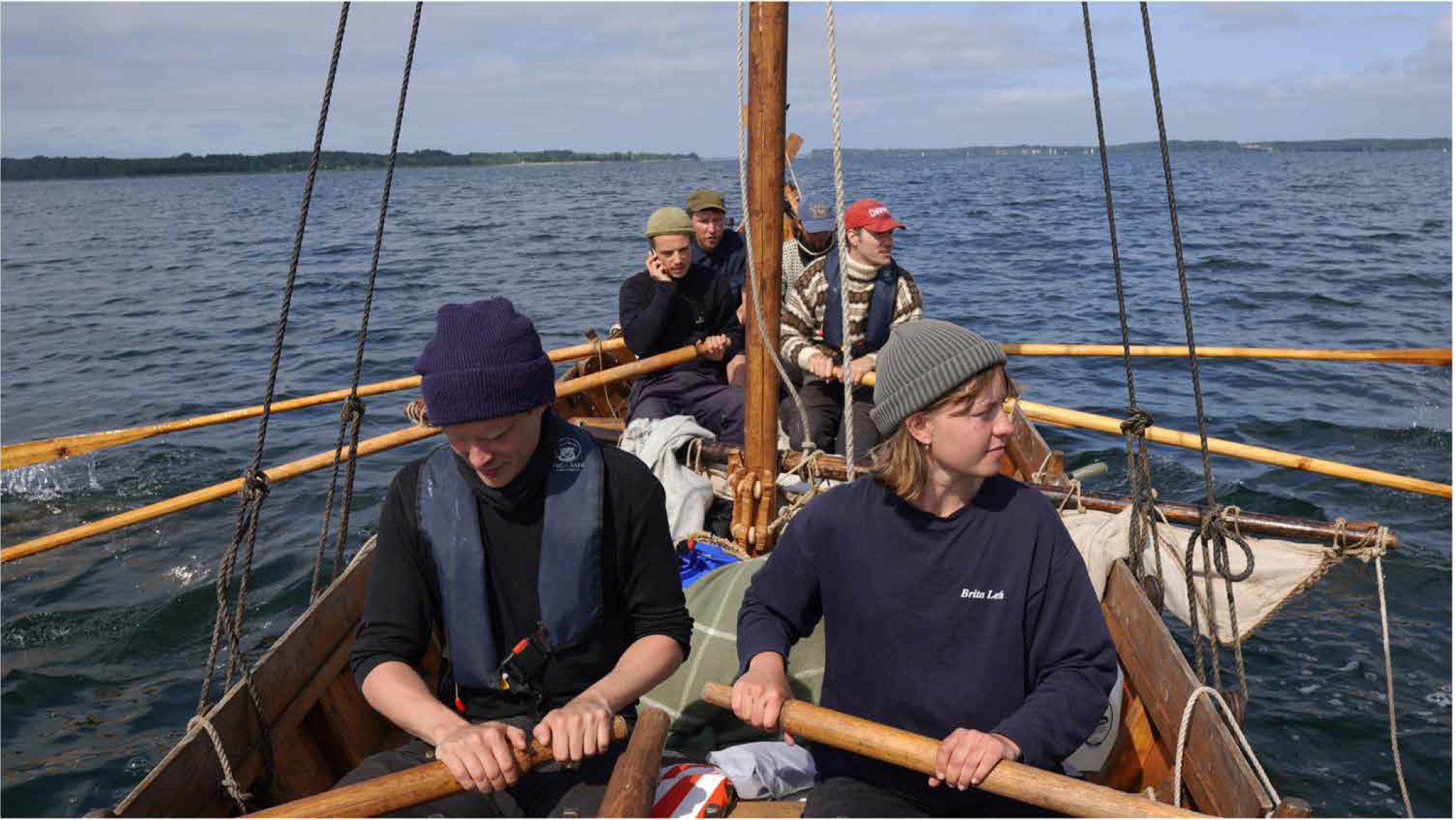 Quatro pessoas remam em um navio nórdico recreativo da era medieval.