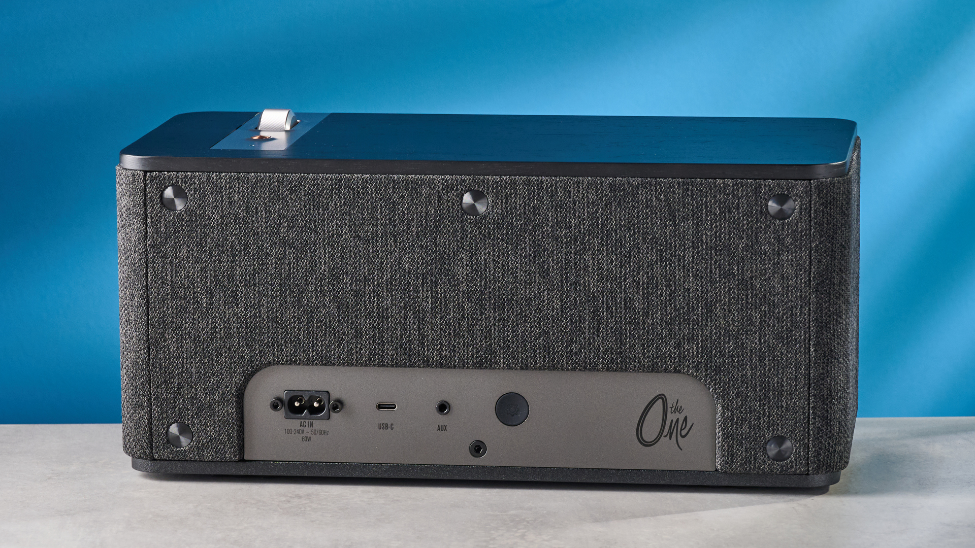 Klipsch The One Plus Bluetooth speaker in matte black photographed in front of a blue background.