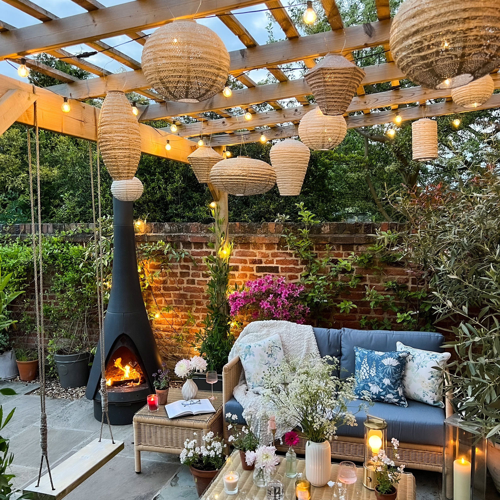 Wooden pergola with plants around  it and lanterns