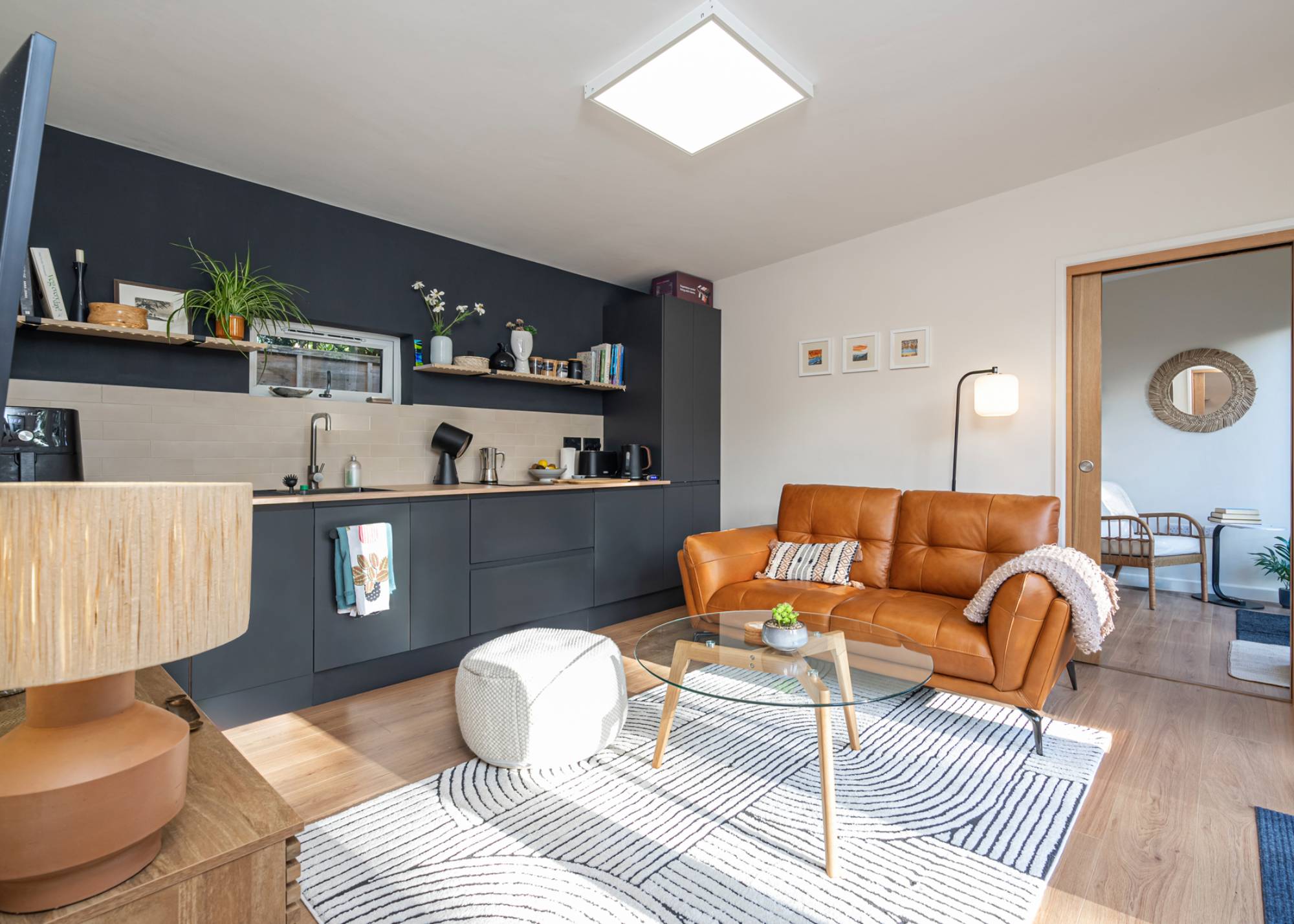 modern living room with kitchenette, leather sofa and white rug