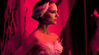 Natalie Portman as Nina Sayers wearing a white ballet costume and standing in a pick room during the thriller movie Black Swan.