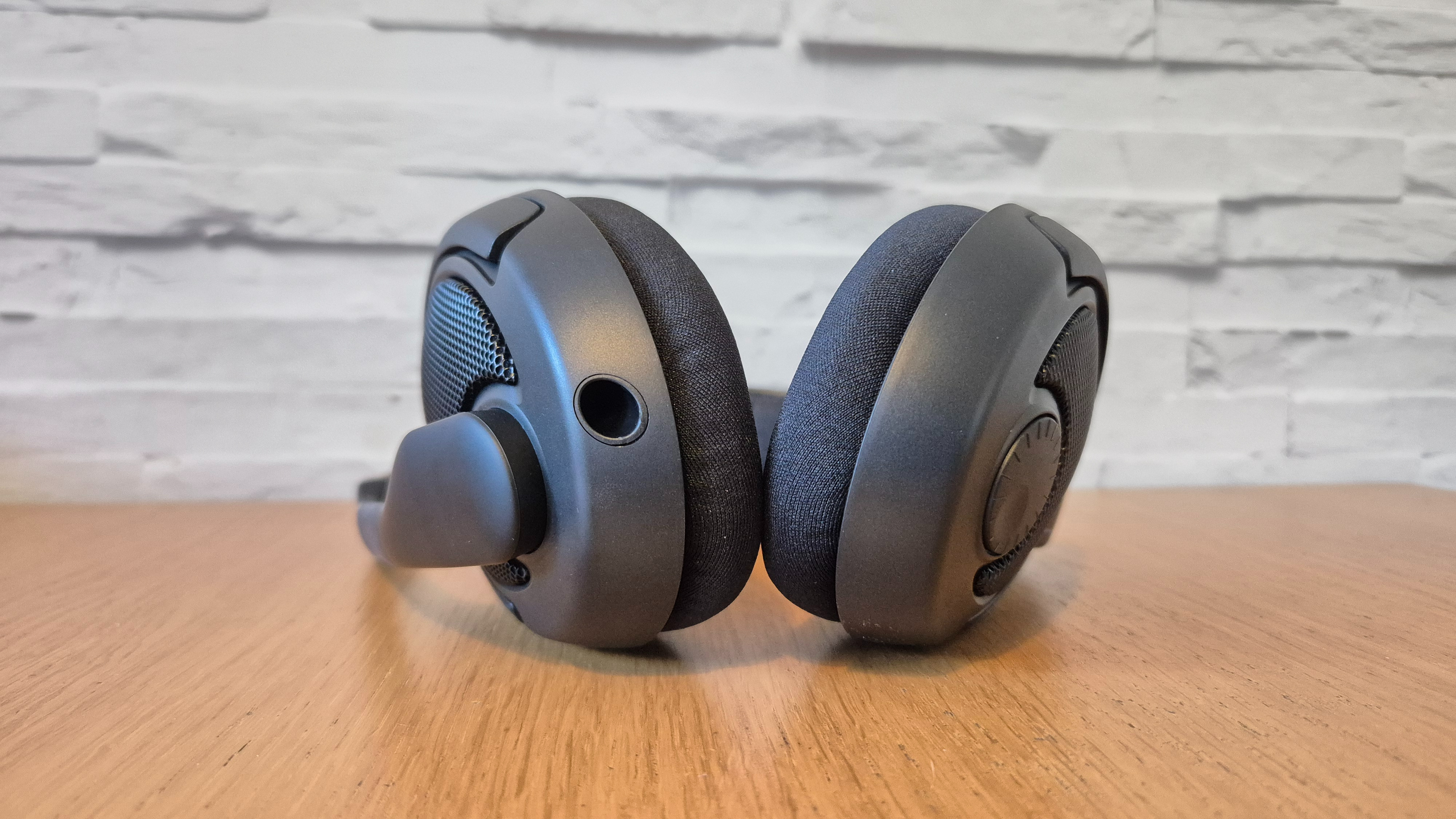 The Drop + Epos PC38X headset on a wooden surface in front of a white brick wall