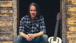 Myles Kennedy sitting on a porch next to a guitar