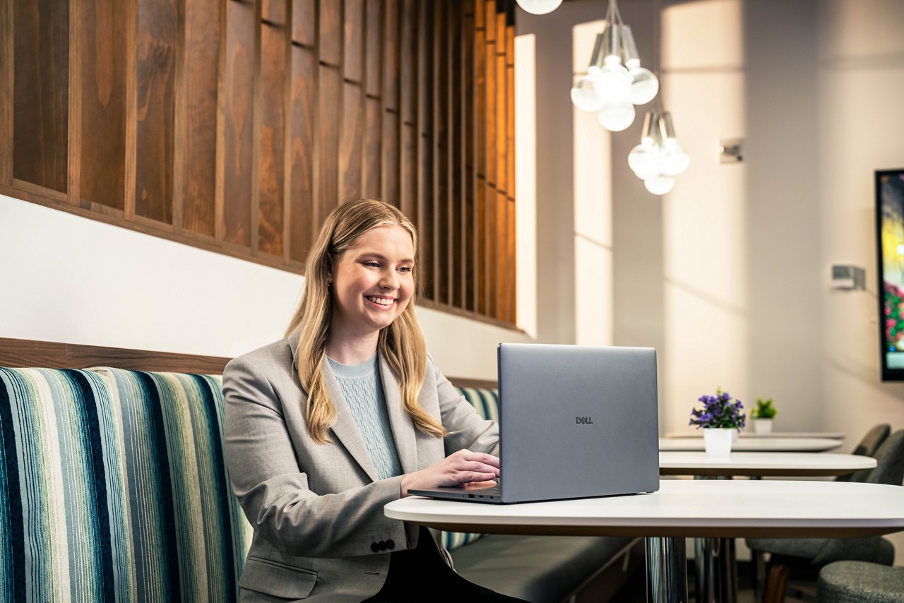 Woman in cafe smiling while using Dell laptop
