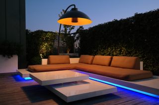 Modern garden with sleek corner sofa and electric patio heater that looks like a floor lamp