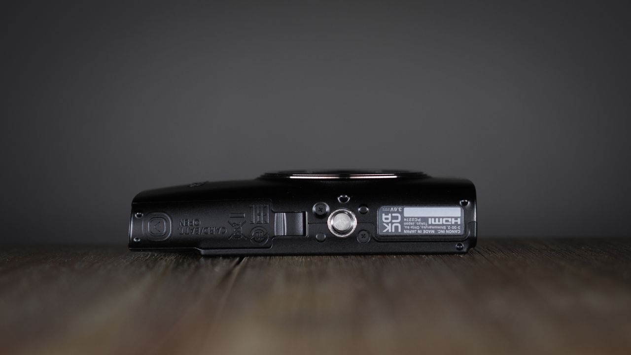 Canon Ixus 285 HS A on a wooden surface against a dark background