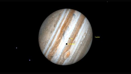 A close up of the planet Jupiter in the darkness of space with a labeled dot for its moon Io.