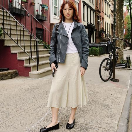 Woman wears khaki skirt white tee and jacket with flats