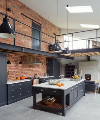 Kitchen with a polished tiled floor in white, light grey and a pair of dark grey or black storage units and kitchen island with white worktops.