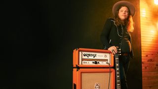 Marcus King wears a wide-brimmed hat and leans against his new signature Orange tube amp.