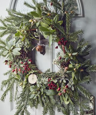 Close up of a festive wreath containing foliage, berries and rose hips, on a grey front door