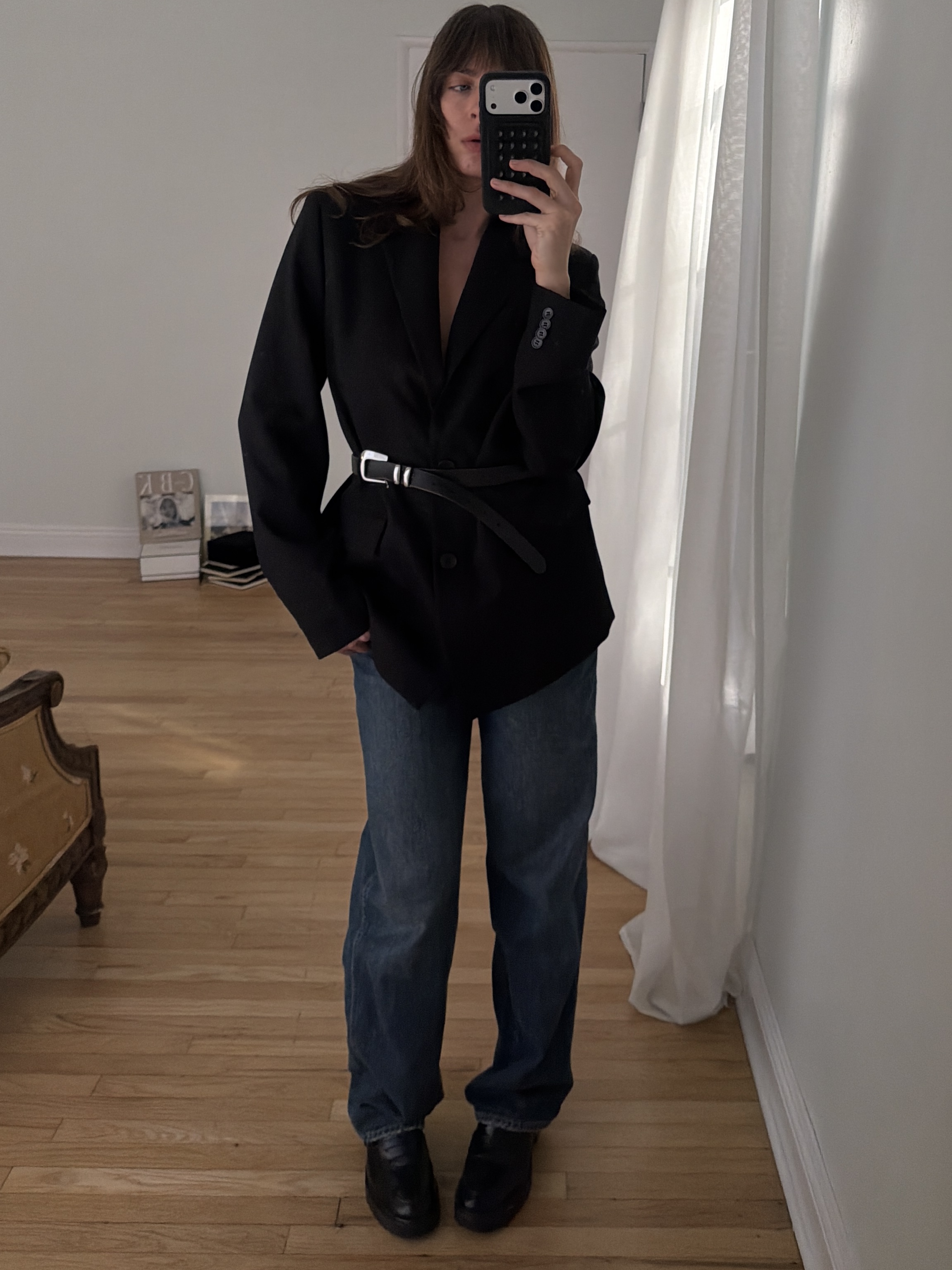 Kathryn Zahorak posing in mirror wearing black blazer, belt, baggy jeans, black boots