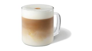 Glass mug with white foam containing Starbucks Latte Macchiato