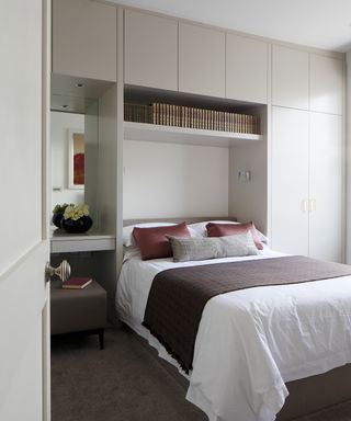 Built-in gray cabinetry surrounding a bed as an example of small bedroom storage ideas.