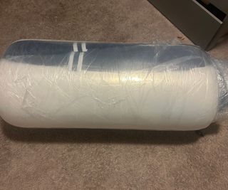 Brooklyn Bedding Signature Hybrid Mattress in plastic wrap against brown carpet.