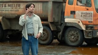 Derek smokes a cigarette in front of the Rhodes and Miller construction truck in Toxic Town