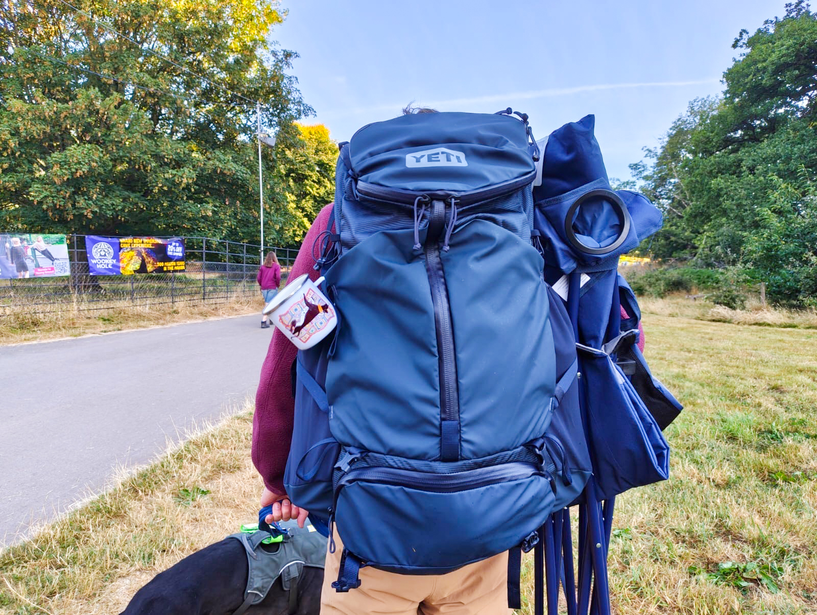 A person wearing the Yeti Skala in blue, carrying a camping chair and walking a dog