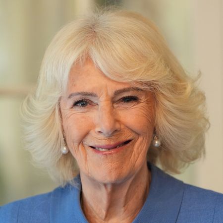 Queen Camilla wearing a blue coat and smiling