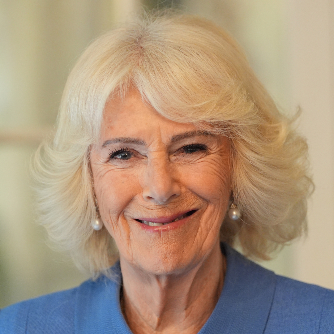 Queen Camilla wearing a blue coat and smiling