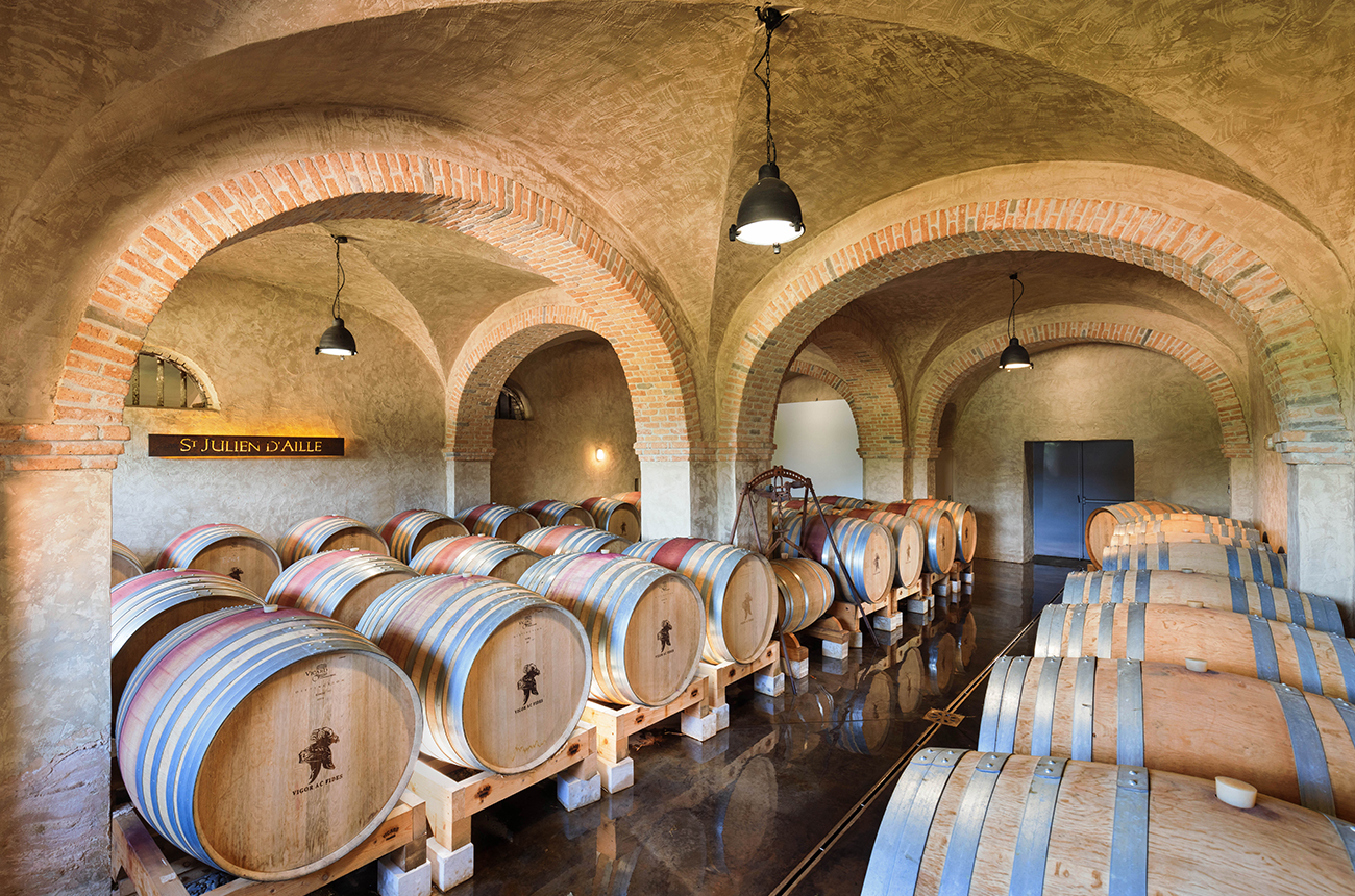 Oak barrels in a cellar, with brick arches.