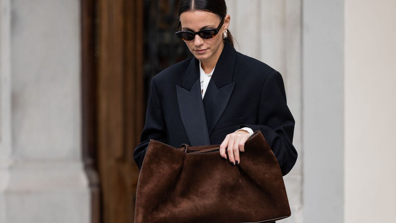 A woman clutching a brown suede bag with a brown manicure, a key winter nail trend