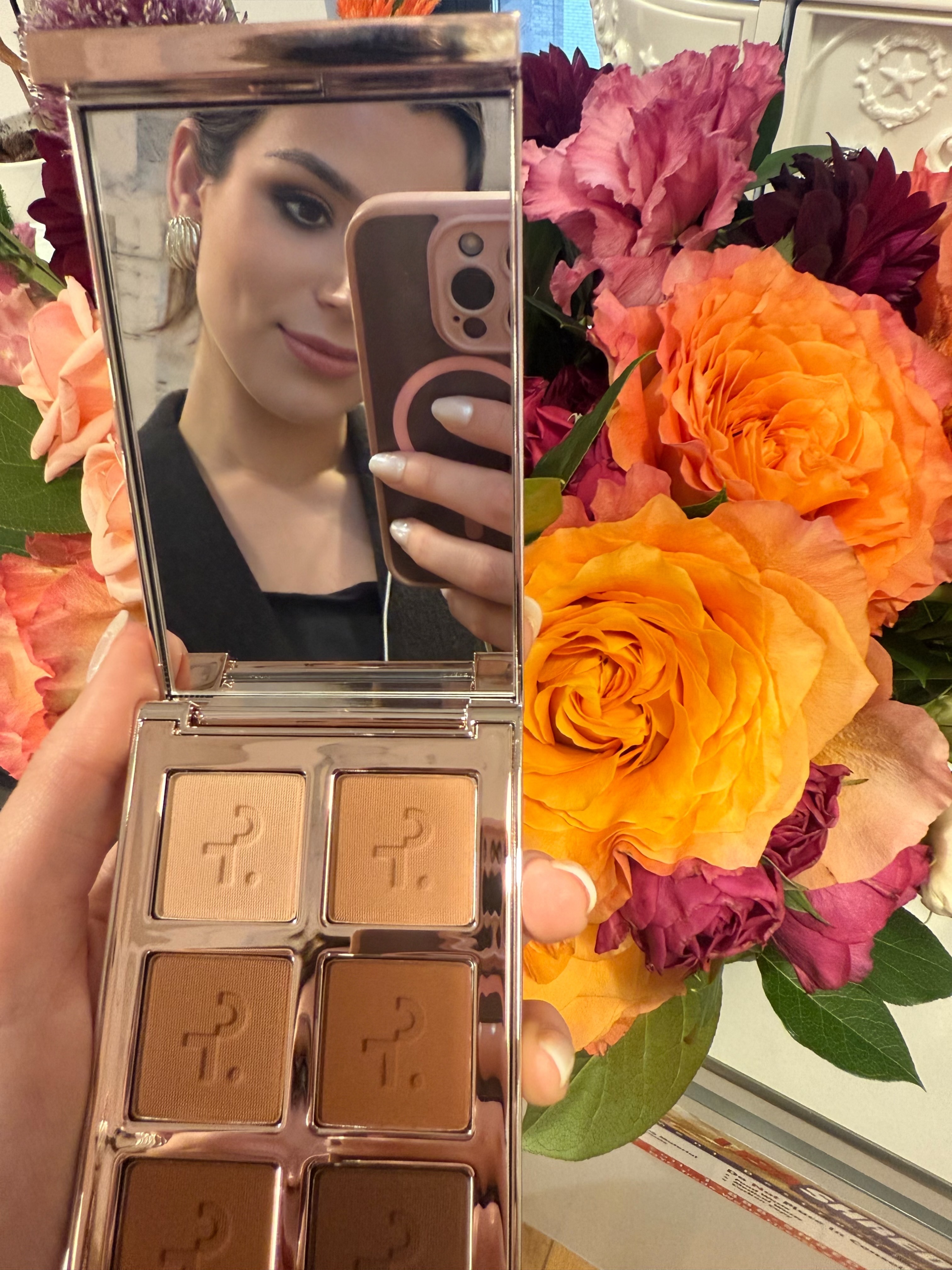 girl looking into the mirror on a six pan eyeshadow compact and taking a selfie on her phone