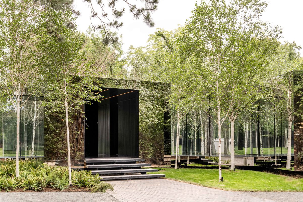 A house with silver berch trees around and with reflecting walls that make it look invisible