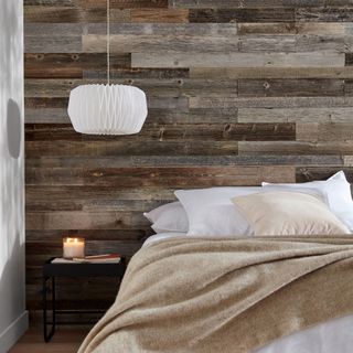 Bedroom with reclaimed wood wall panelling behind bed