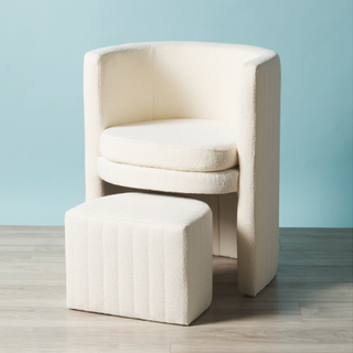 A boucle accent chair with high arms and arched back alongside a matching half-moon boucle ottoman that fits underneath