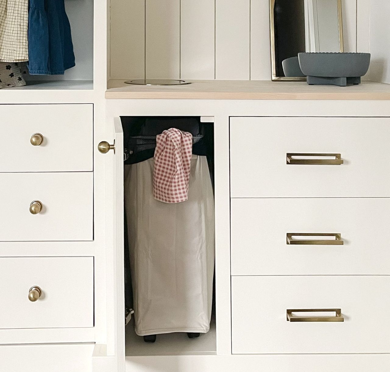 A kid&#039;s closet with an open cabinet door revealing a concealed laundry basket