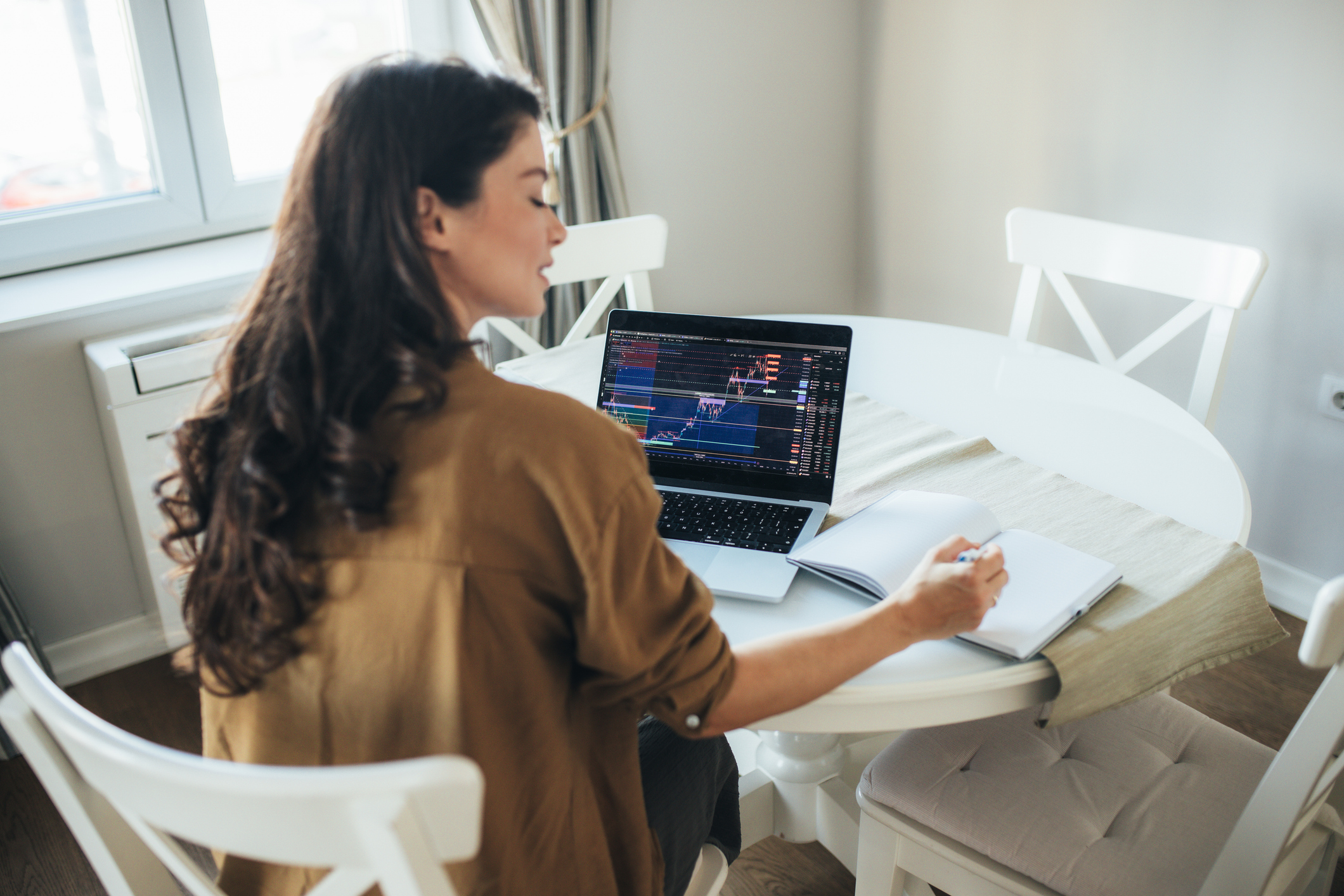 A young woman is sitting in her home and attentively observing the stock market 